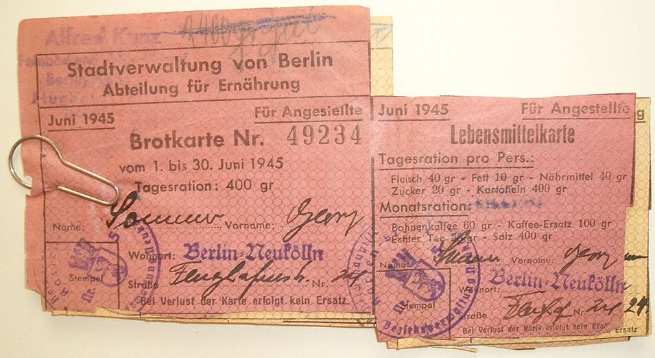 Ein amtliches rotes Papier mit verschiedenen Stempeln und handschriftlichen Eintragungen. Ringsherum sind offensichtlich verschiedene Stücke abgeschnitten worden.